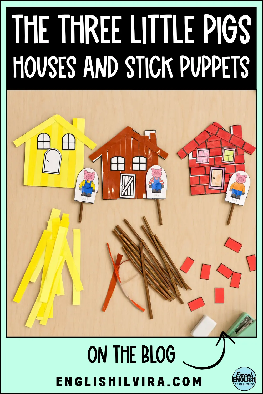 Three Little Pigs craft houses in yellow, brown and red, with pig stick puppets and building materials on a desk.